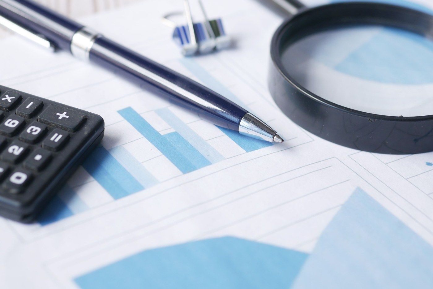 Calculadora, gráfico e lupa sobre uma mesa, representando a revisão de formulários
